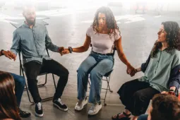 Personas en circulo sentadas tomadas de la mano