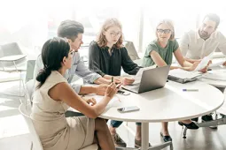 Equipo de trabajo dialogando en mesa con computador