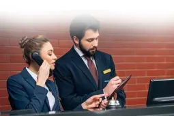 Dos personas en recepción de hotel revisando información