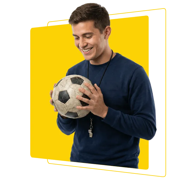 Hombre entrenador sosteniendo balón de fútbol y sonriendo en contexto de educación física, deporte y formación integral